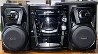 Front view of black Panasonic 5-CD changer stereo system with cassette deck, radio tuner, and two matching speakers.