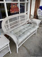 Loveseat with tufted cushion and adjacent side table on concrete porch