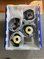 Top-down view inside clear plastic bin showing four bundles of 45 RPM records wrapped in plastic.