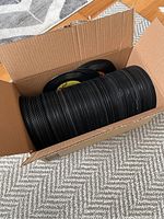 Open cardboard box filled with approximately 50 black vinyl 45 RPM records stacked vertically and horizontally.