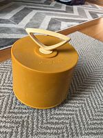 Yellow plastic Disc-Go-Case record caddy with handle on lid, sitting on carpeted floor.