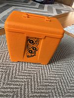 Closed bright orange LustroWear record caddy with musical motif on front