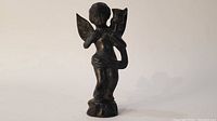 Side view of bronze cherub candelabrum showing figure standing with wings and candle holder.