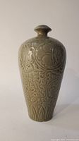 Front angle view of the celadon vase showing floral raised decoration and overall shape.