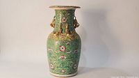 Full frontal view of vase showing green enamel ground with pink floral motifs and flared rim.