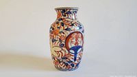 Front and side views of a small Japanese Imari porcelain vase with traditional red, blue, and gold floral and abstract patterns