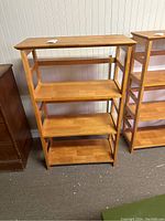 Front view of the wood bookcase showing all four shelves and rectangular side cutouts.