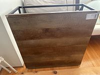 Coffee table shown resting on its side, displaying the wooden top surface with natural grain and a price tag attached.