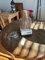 Front view of assembled Cuisinart food processor on wooden table beside two metal disc attachments.