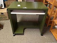 Green Ikea computer desk on wheels with pull-out keyboard tray, showing angles and cutouts on bottom front for cables.