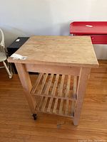 Wood kitchen cart with two slatted wooden shelves and solid wood top, showing natural wear.