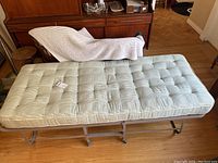 Top view of the roll away bed with mattress showing tufted design and light green striped pattern.