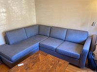 Full view of grey L-shaped sectional sofa with chaise on left against a beige wall