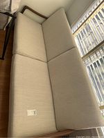 Top-down view of entire teak couch showing off-white seat and back cushions and teak frame