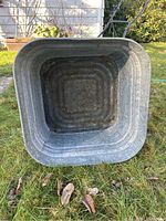 Top-down view inside metal washing tub showing square shape with rounded corners, embossed ridges, and rust spots.