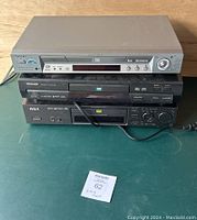 Three DVD players stacked: silver Sony on top, black Toshiba in middle, black RCA on bottom. Toshiba missing power cord, all untested.