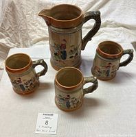 4 Vintage Hand Painted Bavarian Beer Steins and Pitcher together showing detailed folk art and textured handles