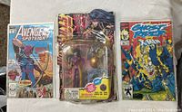 Photo showing the Wild Cats Voodoo action figure packaged in blister pack between three Marvel comics: Avengers Spotlight, Ghost Rider, and X-Men comics.