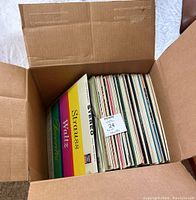 Cardboard box with about 40 vintage vinyl records inside, showing colorful record covers including Strauss Waltz Favorites.