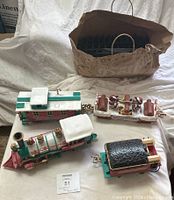 Top down view of Christmas themed toy train components with paper bag containing track pieces in background.