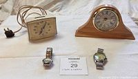 Lot of 2 clocks and 2 watches, showing white electric clock with cord and wooden mantel clock, plus 2 wristwatches.