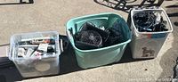 Overview photo showing three tubs containing electrical and electronic equipment and cords placed outdoors