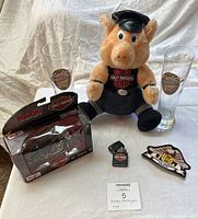 Photo showing entire lot with two glass drinking glasses, plush pig, boxed Harley model bike, HOG patch, and Zippo lighter