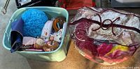 Wide view of the tote filled with toys and the clear bag of blankets alongside the small plastic stool.