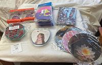 Photo showing all items in lot arranged on a surface including swim caps, bubble poppers, book lights, shower brush, tablet holder, and mouse pads.