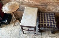 Photo showing a round wooden side table, a rectangular upholstered bench with light-colored fabric, and a square foot rest with diamond-patterned fabric upholstery