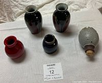 Front view of four vintage ceramic vases and one potpourri holder arranged on white surface