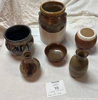 Front view of six vintage ceramic items arranged on a cloth background showing various shapes and glaze finishes.