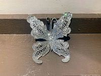Front view of the sparkly silver butterfly clip showing intricate wing design and glitter detail.
