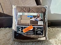 Packaged 3-piece sofa protector cover in light brown color, showing front packaging with brand and use images.