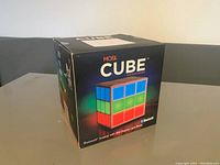 Front and side view of the sealed box showing the Mobi Cube branding and image of a cube-shaped Bluetooth speaker with colorful LED lights.