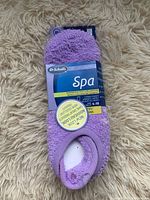 Photo of a new pair of mauve Dr. Scholl's Spa socks with tags attached, size large, lying on a beige shaggy surface.