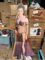 Full view of the life-size Princess Leia cut-out standing against boxes in storage.