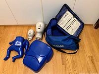 Photo showing the CPR training mannequin torso, two heads, and bag on the floor
