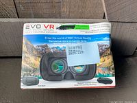 Front view of boxed EVO VR virtual reality headset showing product image and included Bluetooth controller.