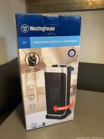 Front view of unopened box showing the 17 inch vertical ceramic heater and its key features including oscillation.