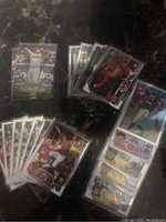 Photo showing multiple baseball cards including players from the San Diego Padres and other MLB teams, some cards with Technicolor and Silver Prizm effects, placed on a dark surface.