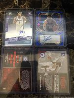 Front and back of four NBA basketball cards showing player images, team logos, autographs and serial numbers.