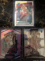 Front of three Evan Mobley rookie basketball cards. One in USC Trojans jersey, one Cleveland Cavaliers pink SP Marquee Prizm, one Cleveland Cavaliers silver Mosaic Prizm.
