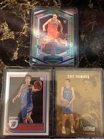 Front side of three rookie basketball cards including Josh Giddey Prizm in a protective sleeve, and two Chet Holmgren cards from NBA Hoops and Contenders Stallions series.