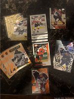 Image showing a mix of hockey cards on a dark tabletop, includes Young Guns gold parallel cards of a player number 37, die cut holographic cards, and Dazzlers insert cards.