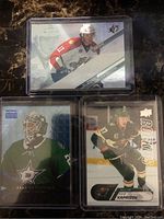 Front view of three NHL rookie hockey cards featuring Kaprizov, Oettinger, and Huberdeau in protective cases.