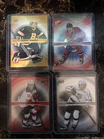 Four NHL rookie hockey cards displayed showing their fronts featuring players in action with holographic backgrounds.