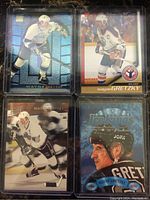 Front view of four Wayne Gretzky hockey cards in plastic sleeves showing different designs and team uniforms.