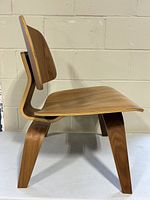 Side profile of molded plywood chair showing bent legs and curved seat
