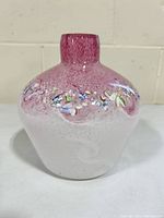 Front view of signed decorated art glass vase with mottled pink and white colors and raised floral decorative band.